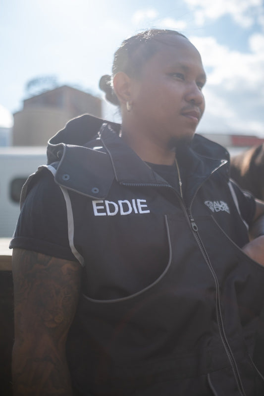 Dog trainer wearing a black Alpine Dog training vest with reflective piping and embroidered chest pockets outdoors
